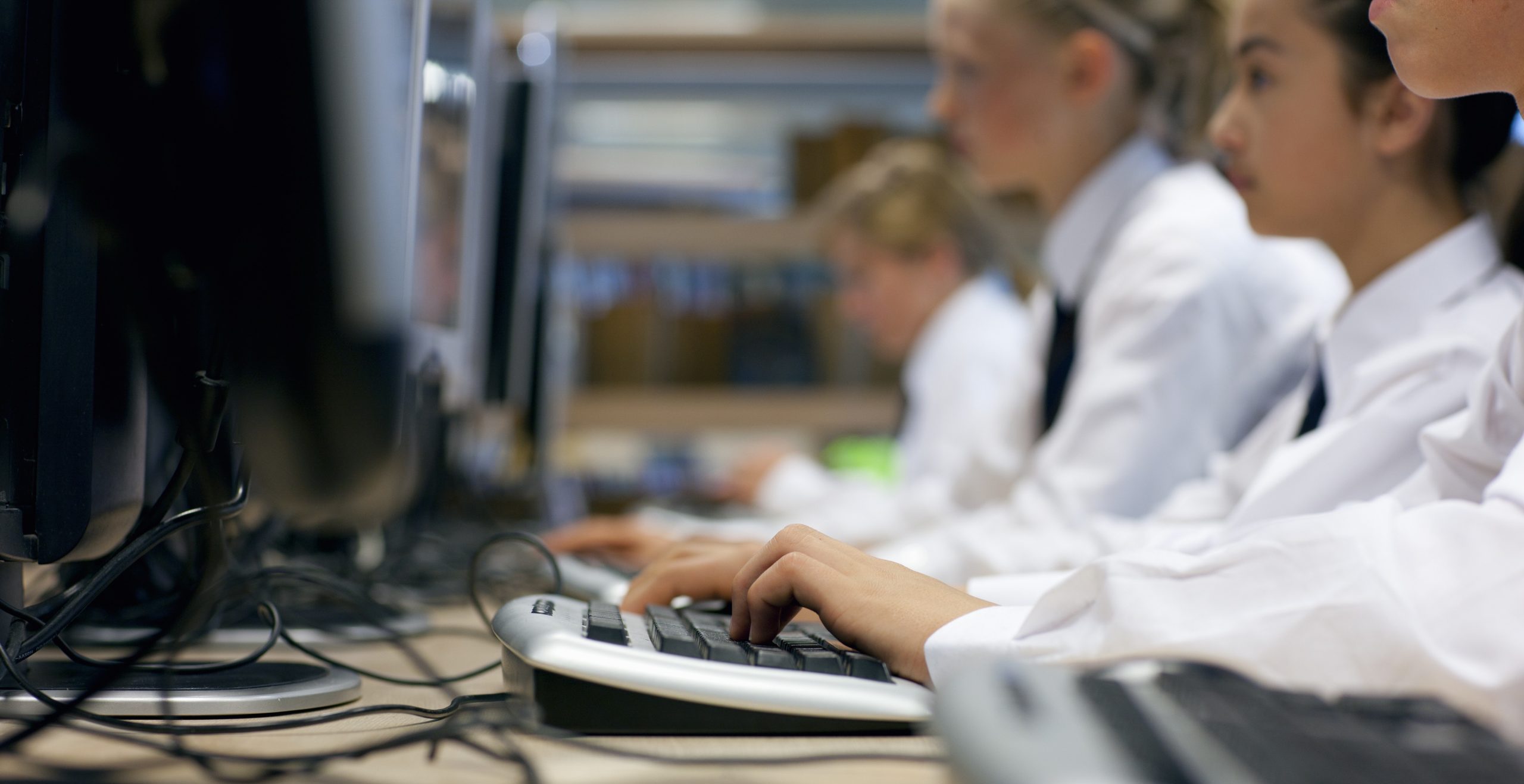 Line of high school students in uniform using computers in library | SSITA